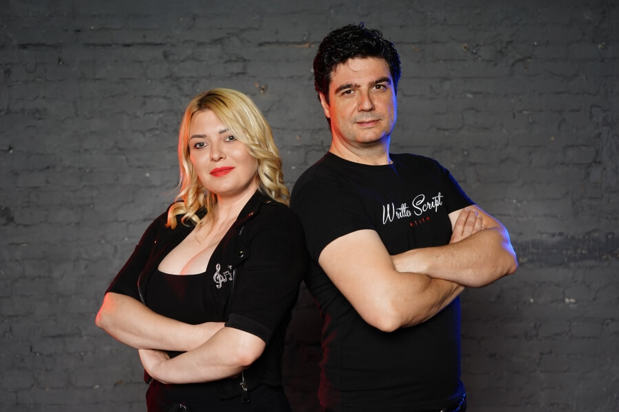 Žena i muškarac u crnim majcama sa prekrštenim rukama okrenuti leđima jedno drugom