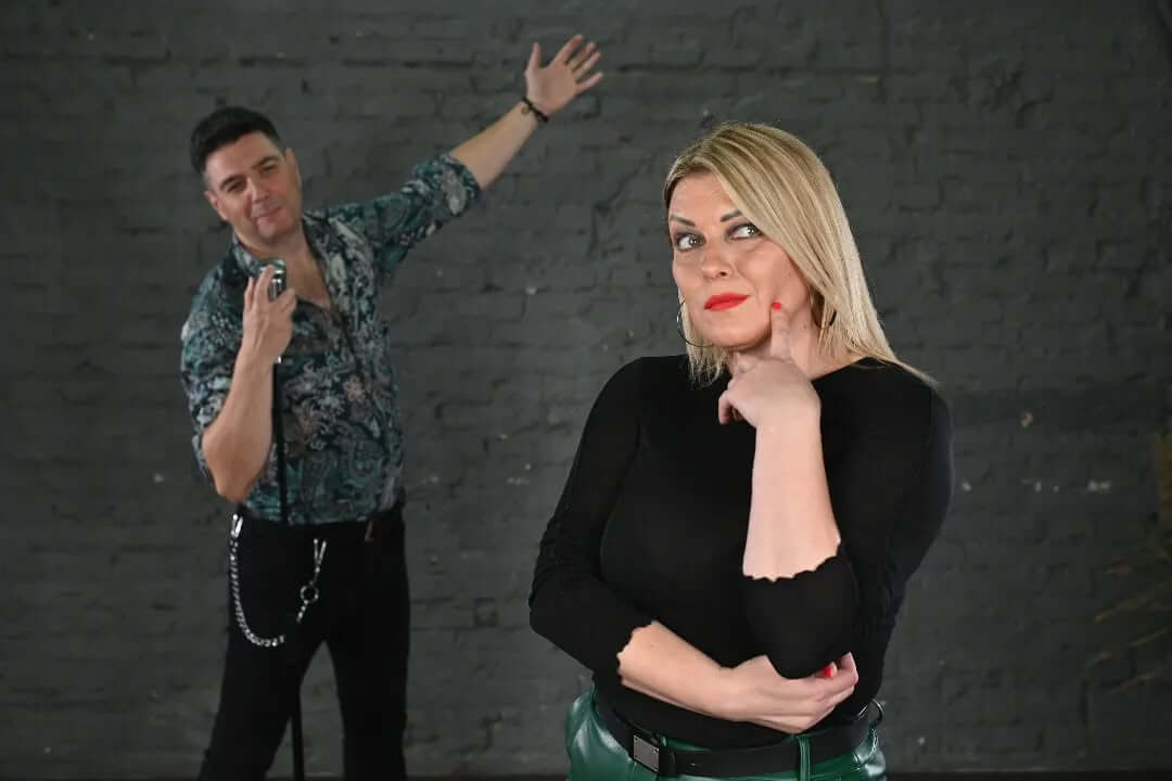 Zamišljena žena u crnoj majici i muškarac  sa mikrofonom u šarenoj košulji