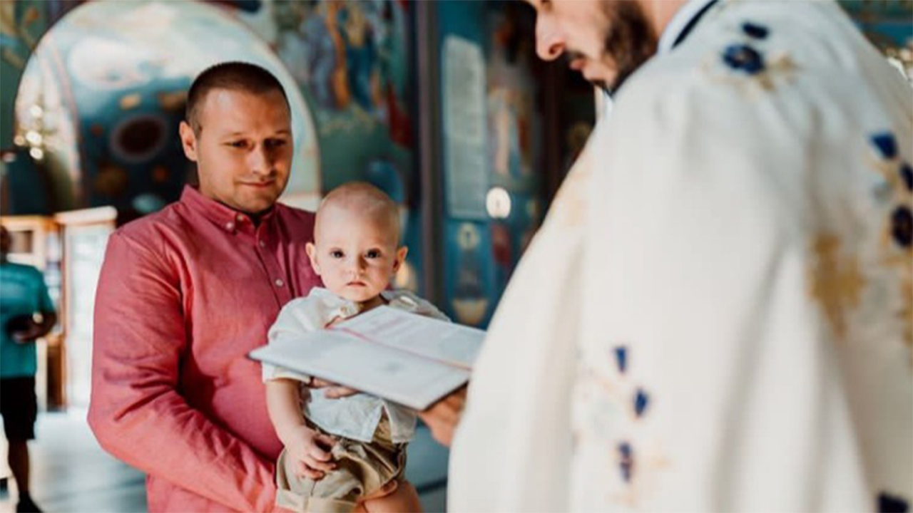 otac drži dete u crkvi na krštenju