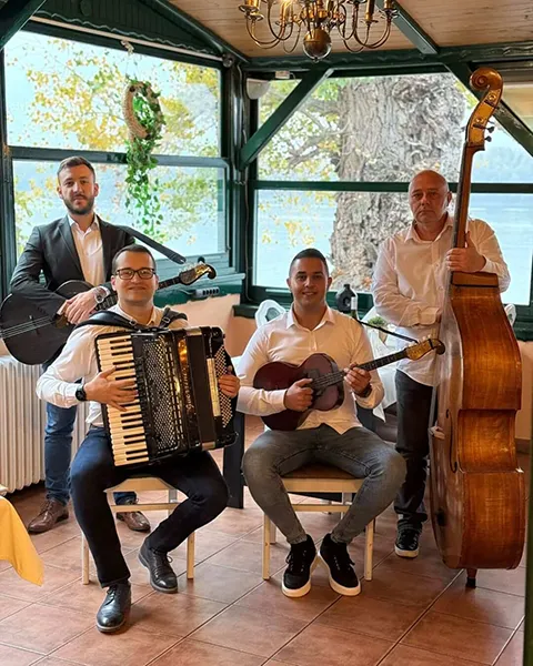 Tamburaši za proslave u restoranu, muzičari sa harmonikom, tamburom, gitarom i kontrabasom poziraju za grupnu fotografiju