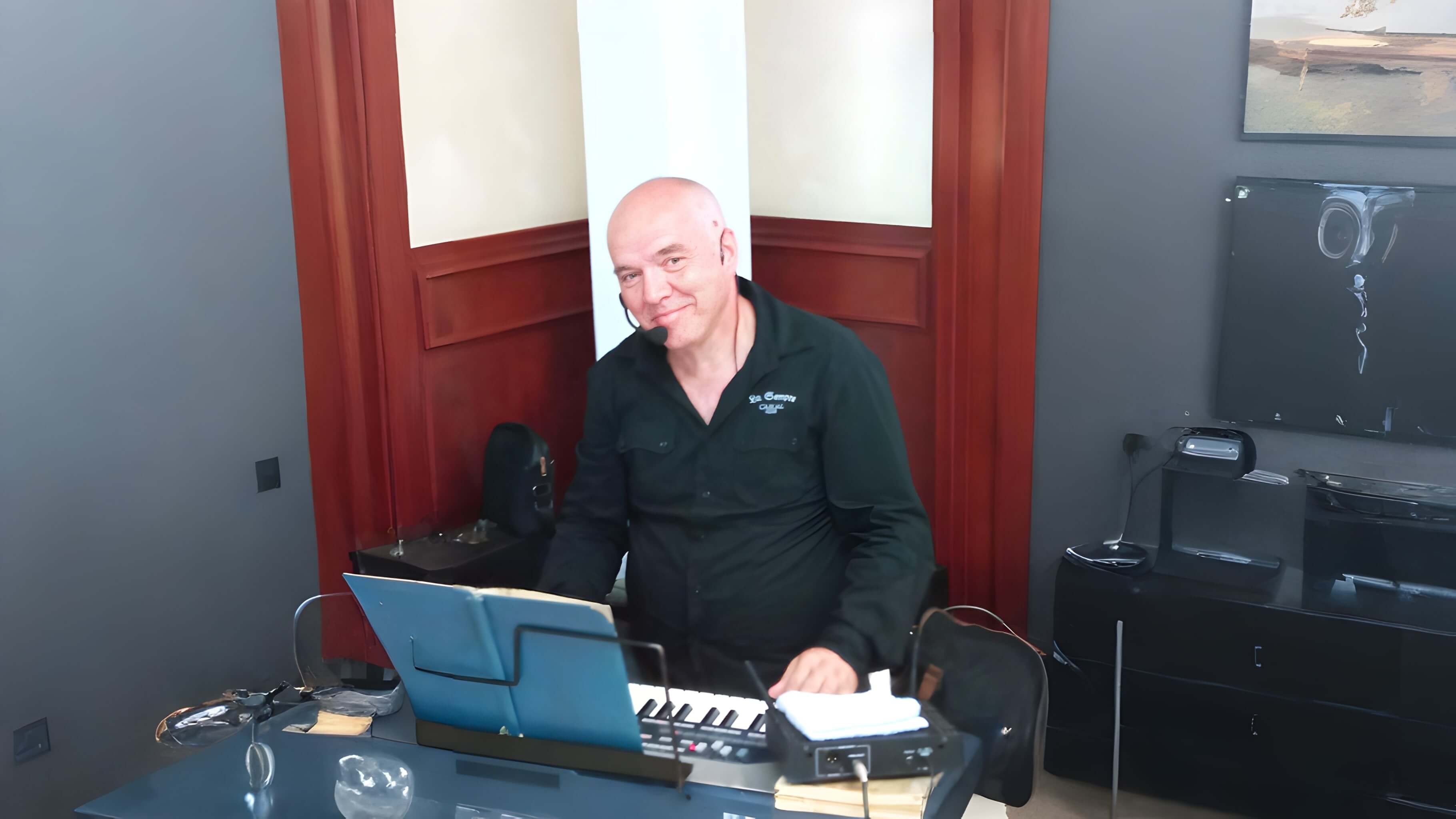 muškarac koji se osmehuje u crnoj majici za klavijaturom