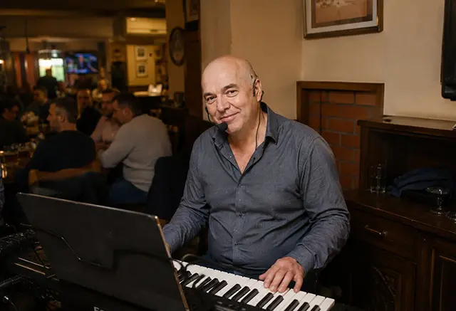 Zoran Nestorović svira klavijaturu i peva sa bezicnim mikrofonom na proslavi u kafani